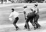 A man is chased by three Portland policemen during the 1967 Irving Park riot in Albina, an event that had begun as a peaceful rally by black activists.
