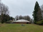 field with child on bench in front of a large brick structure with a domed roof