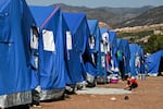 A child plays next to relief tents near a military field hospital in the village of Asni near Moulay Brahim in al-Haouz province in the High Atlas mountains of central Morocco on September 11, 2023.