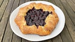 A marionberry galette with folded edges encrusted in sugar.