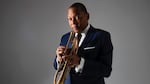 Photo of the trumpet player Wynton Marsalis holding his horn in a blue navy suit.