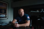 A portrait of Dan Bongino seated at a table.