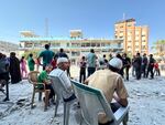 Injured men sit outside the scene of destruction caused by an Israeli strike on a U.N. school in Nuseirat in central Gaza.