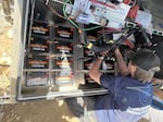Student field technician Ben Aldrich wires 16 heavy-duty batteries in the power source panel.
