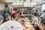 Retired chef and cooking instructor Brenda Madden gathers students around a table to enjoy their creations from the afternoon’s lesson on French cuisine.