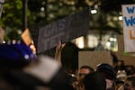 A protester holds a sign critical of Mayor Ted Wheeler, who is also police commissioner, and his use of tear gas against demonstrators in Portland, Ore., July 22, 2020.