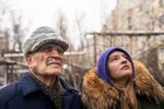 Petro Shevchenko, (left) stands with his grandaughter, Olena Parkhomenko, as they look at the damaged apartment building. Shevchenko, 85, lives alone on the 7th floor and has cuts on his face from the attack.