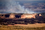 Smoke from the Snyder Fire appears over a tall rock formation near Thompson Springs, Utah, on June 28.