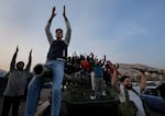 Syrian citizens stand on a government forces tank, that was left on a street, as they are celebrating during the second day of the take over of the city by the insurgents in Damascus, Syria, Monday, Dec. 9, 2024.