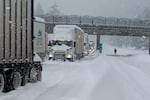 In this photo provided by the Oregon Department of Transportation, trucks are parked in the snow along Interstate 84 in the Columbia River Gorge about 60 miles east of Portland, Ore., Monday, Jan. 3, 2022. Heavy snow and high winds forced officials to close dozens of state roads in eastern Oregon on Monday and Interstate 84 was shut down through the Columbia River Gorge, while blowing snow also closed a major road over the Cascade Mountains in Washington.