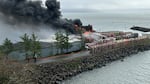 A cloud of black smoke rises above a large fire at a building located on the shore of the Pacific Ocean in Southwest Washington.