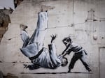 Graffiti of a child throwing a man on the floor in judo clothing is seen on a wall amid damaged buildings in Borodyanka on Friday.