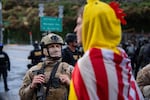 A federal agent and protesters stand in front of the Immigration Customs and Enforcement building in Portland, Ore. on Saturday, Oct. 25, 2025. A crowd of about 100 gathered in front of the building to protest that afternoon.