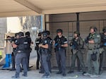 A Medford Police Department SWAT team stands just outside Oakdale Middle School, carrying practice guns before making their way inside on June 22, 2023.