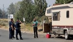 Bend Police officers talk with Clausen Road resident Christopher Moe, before crews remove his trailer in Bend on July 17, 2023.