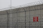 FILE - Barbed wire fencing is shown behind a sign in English and Spanish in a recreation yard used by detainees during a media tour of the U.S. Immigration and Customs Enforcement detention center, Dec. 16, 2019, in Tacoma, Wash. People detained in this facility receive legal advice from the Northwest Immigrant Rights Project, one of the advocacy groups currently suing the Trump administration for blocking legal access for detained undocumented immigrants.
