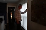 Bo Mullan opens the blinds at his home in Portland, Ore on March 4, 2026. Mullan, who has a terminal illness and high medical bills, said the ordeal with the city has been deeply distressing.