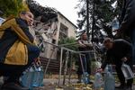 Residents fill bottles with water from a public spigot in front of a bombed-out student dormitory in the coal mining town of Dobropillya, Ukraine, on Oct. 17.