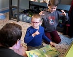 (Left to right) Sara Weith talks with Oli, 7, as big brother Gus, looks on at their home in Portland, Dec. 29, 2022. 