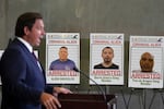 Posters of alleged criminals who officials said were arrested in a recent immigration enforcement operation are displayed as Gov. Ron DeSantis speaks during a press conference at the South Florida office of U.S. Immigration and Customs Enforcement and Enforcement and Removal Operations, Thursday, May 1, 2025, in Miramar, Fla.