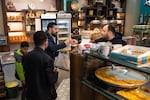 A customer pays for desserts at Mahrouseh, which is a sweet shop owned by a Syrian refugee family from Aleppo.