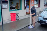 A worker sweeps broken glass in front of A Street Print and Parcel in Ashland following an officer-involved shooting on Oct. 26, 2026.