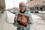 Linda Navarre, a member of the Bonner County Human Rights Task Force, poses for a photo Monday, Feb. 7, 2022, in downtown Sandpoint, Idaho, as she holds a 1997 issue of Parade Magazine that contains an article mentioning the efforts of herself and others fighting against conservative extremist groups in northern Idaho. Today, she says political divisions in the town are getting even wider, and a growing number of real estate companies seeking to capitalize on that trend are advertising that they can help people move out of liberal bastions like Seattle and San Francisco and find homes in places like rural Idaho.