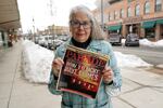 Linda Navarre, a member of the Bonner County Human Rights Task Force, poses for a photo Monday, Feb. 7, 2022, in downtown Sandpoint, Idaho, as she holds a 1997 issue of Parade Magazine that contains an article mentioning the efforts of herself and others fighting against conservative extremist groups in northern Idaho. Today, she says political divisions in the town are getting even wider, and a growing number of real estate companies seeking to capitalize on that trend are advertising that they can help people move out of liberal bastions like Seattle and San Francisco and find homes in places like rural Idaho.