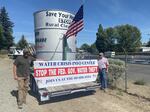 Two men hold a sign that reads "stop the Fed. Gov. water theft."