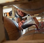 Kimmel tops the wine barrels at her home in White Salmon, Wash., on July 14, 2026. Topping is the process of replacing the wine lost to evaporation, which keeps the wine from oxidizing and spoiling.