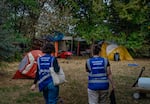 Lillian Risser, left, and Sophia Loveland, right, approach an encampment in Humboldt Park on Sept. 23 in Chicago. Risser and Loveland are outreach workers for Thresholds, a mental health care provider in Illinois that works to move people out of encampments into more permanent housing.
