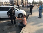 A man involved in the brawl recovers from mace as police stand by in Bend, Oct. 3, 2020. 