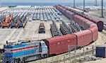 Heavy equipment and cars are prepared for shipment by rail in Yantai, eastern China's Shandong province, on June 20, 2026.