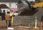 FILE: A construction worker directs a backhoe to drop gravel off in the trench of the Glisan Landing construction site in Portland last summer.