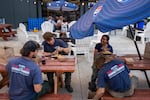 United States Fire Service firefighters, formerly a Bureau of Land Management crew, eat Thai food together after getting off of the line of the Bench Fire on a smokey evening in Madras, Ore., on July 27, 2026.