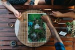 Picture depicts three people gathered around a gameboard.