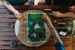 Picture depicts three people gathered around a gameboard.