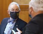 Two people wearing suits and masks talk inside the Oregon state Capitol building.