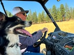 Dean Defrees drives the side-by-side off-road vehicle on the Defrees Ranch, alongside Chuck, one of his ranch dogs. Chuck is one year old and still learning the finer points of his job herding. 