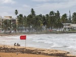 Tourists sit on La Pared beach as Ernesto passes by Luquillo, Puerto Rico, on Tuesday.