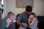 Tyler Hoyt holds his daughter, Winnie, while his son, Emmett, looks on. Emmett also qualifies for Medicaid because of his family's income.