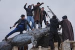Residents topple a statue of a female Kurdish fighter after the takeover of the town by Syrian government forces from U.S.-backed Syrian Democratic Forces (SDF), in Tabqa, eastern Syria, on Sunday.