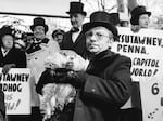 Jim Means holds up a sleepy Punxsutawney Phil at daybreak on Feb. 2, 1980. The groundhog's "Inner Circle" dresses the same today.