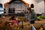 Five-year-old Eliza Gamage picks up a watermelon, pleasantly surprised by her own strength, as they pick out food at One Life Food Pantry, located in Real Life Foursquare Church in Vancouver, Wash., on Nov. 1, 2025. With all the uncertainty surrounding SNAP, it was their first time at the One Life and their second time at a food bank in two weeks.