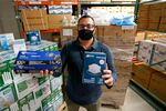 Ray Bellia holds up personal protective masks and gloves, used by medical and law enforcement professionals, in the warehouse of his Body Armor Outlet store on Wednesday, Dec. 9, 2020, in Salem, N.H.