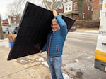 Solar States owner Micah Gold-Markel carries a solar panel from a truck to the house where it will be installed.