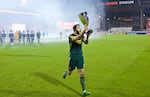 Portland Timbers midfielder Diego Valeri (8) carries the Western Conference Championship Trophy over to the Timbers Army at Toyota Stadium.
