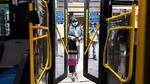 A woman wearing a protective mask enters a city bus on April 23, 2020 in New York City. New York's Metropolitan Transportation Authority approved a benefits program for workers who die of COVID-19-related causes.