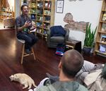 Jon Raymond speaking to a crowd and the house cat, Amber, at JaxDox Cafe & Books.