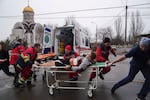 Ambulance paramedics move an injured man on a stretcher, wounded by shelling in a residential area, at the maternity hospital converted into a medical ward and used as a bomb shelter in Mariupol, Ukraine, Tuesday, March 1, 2022. Russian strikes on the key southern port city of Mariupol seriously wounded several people.